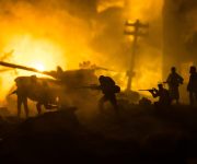 War Concept. Military silhouettes fighting scene on war fog sky background, World War Soldiers Silhouette Below Cloudy Skyline At night. Battle in ruined city.